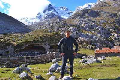 Fernando Abarquero delante de los abrigos para las cabras y ovejas, con Peñacastil al fondo.
